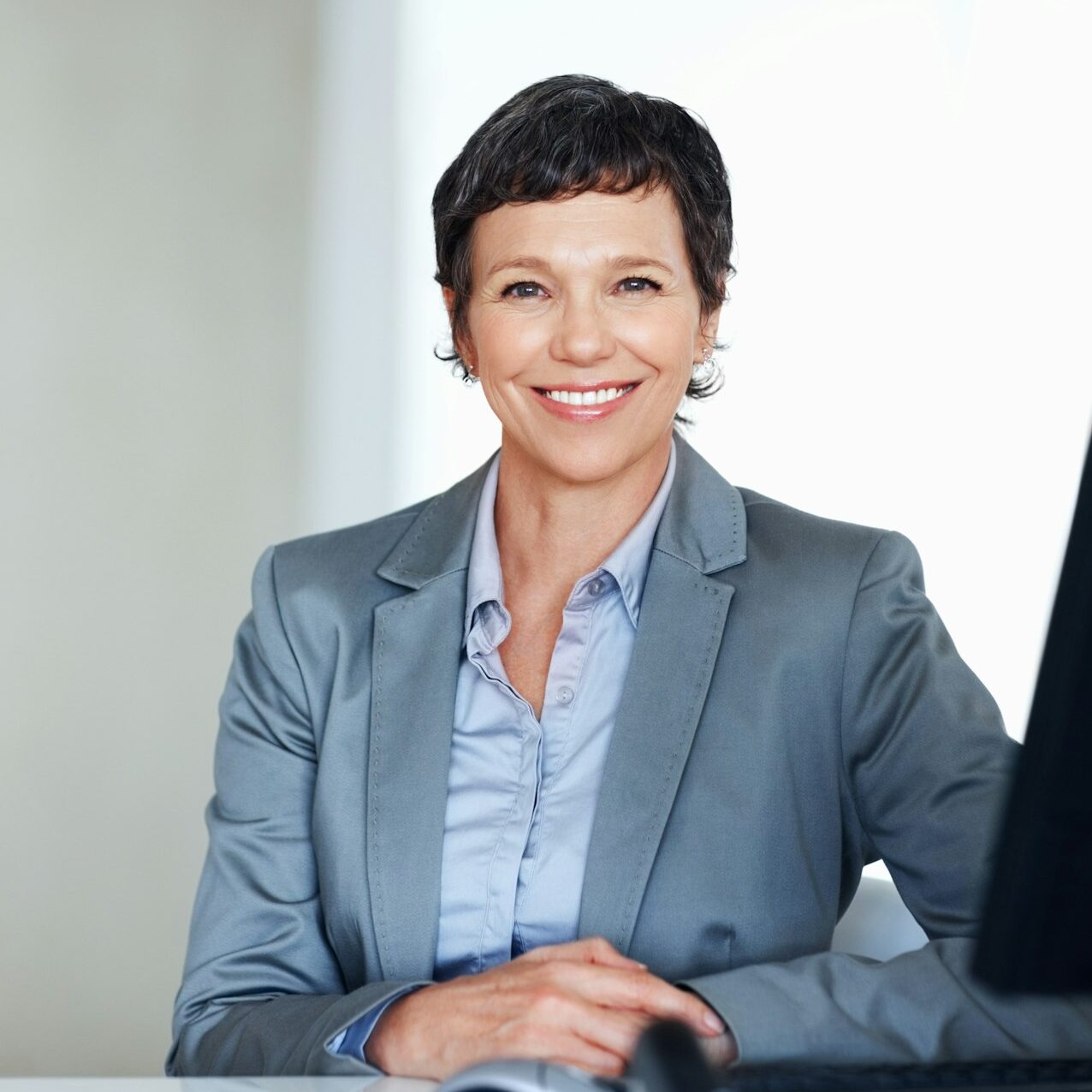 Mature female c-level executive smiling at office desk.